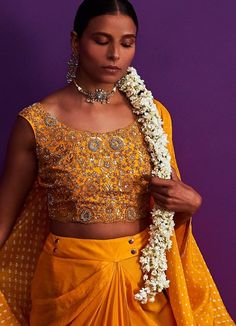 Features a mustard yellow bandhani cape with zari work on sleeves teamed with a heavily embroidered crop top. Completed with a draped lehenga. Composition : Silk Care: Dry Clean Only and Vacuum Storage This product can be customised for sleeves, length of blouse and neckline Delivery : 4-6 weeks as the product is hand crafted. For more information and sizes please contact fabiliciousfashion@gmail.com or visit our Copenhagen studio.About the Designer : Pink City by Sarika, established in 2014, is a young and modern brand that offers modern indo western silhouettes with old world sophistication. With a meticulous eye for detail and an unwavering passion for creating beautifully made clothes, Pink City by Sarika has become synonymous with Indian indo western wear. The brand's distinct style a Cape Sleeves Anarkali Set For Reception And Festivals, Bollywood Style Sharara With Cape Sleeves For Festivals, Traditional Saree With Mirror Work And Cape Sleeves, Traditional Pre-draped Saree With Mirror Work And Cape Sleeves, Traditional Sharara With Cape Sleeves For Reception, Bollywood Style Sharara With Cape Sleeves For Navratri, Festive Lehenga With Cape Sleeves For Diwali, Bollywood Pre-draped Saree With Cape Sleeves For Festivals, Festive Cape Sleeves Lehenga For Reception