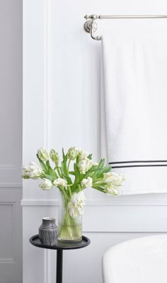 a vase filled with white flowers sitting on top of a table next to a bath tub