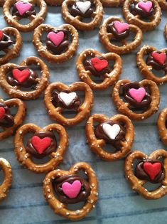 heart shaped pretzels with chocolate and pink hearts on them are ready to be eaten