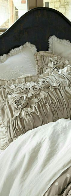 an unmade bed with white linens and ruffled bedspread in front of a window