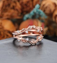 a rose gold wedding band with three diamonds on the top, and leaves in the middle