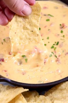 a hand dipping a tortilla chip into a bowl of quesadilla dip