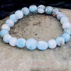 Dominican Larimar Gemstone Beaded Bracelet, Atlantis Dolphin Stone, Calm Luck and Enlightenment, Leo Birthstone, Beach Vibe, Stackable One round Larimar bead to symbolizes one world.  Two oval Larimar beads represent the Sky that stretches endlessly in each direction.  Completing the circle are a carefully selected synergy of natural blue green white and red Larimar gemstone beads laced with copper matrix.  They symbolize the Sea, its' coral, its' depths, and its' mysteries.   ✨The Pfeffars Difference ✨ ☺ Happiness Guaranteed. Our top priority is your complete happiness. Which means we stand by our crystal bracelets 100% no matter what. If you have a problem, we will solve it. Remake it. Whatever it takes. Just reach out to us within 14 days of receiving your bracelet. We're here for you. Aquamarine Turquoise Bracelet For Healing, Turquoise Aquamarine Healing Bracelet, Adjustable Aquamarine Bracelets With Natural Stones, Spiritual Aquamarine Turquoise Bracelets, Spiritual Turquoise Aquamarine Bracelets, Adjustable Aquamarine Beaded Bracelet With Natural Stones, Adjustable Aquamarine Beaded Bracelets With Natural Stones, Handmade Aquamarine Beaded Bracelets, Aquamarine Natural Stones Bracelet For Healing