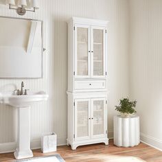 a white bathroom with a sink and cabinet next to a mirror on the wall above it