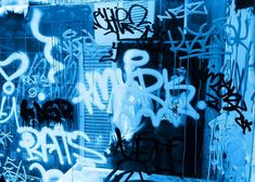 some graffiti on the side of a building with blue light coming from it's windows