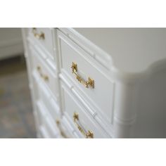 a white dresser with gold handles and knobs on it's drawers in a room