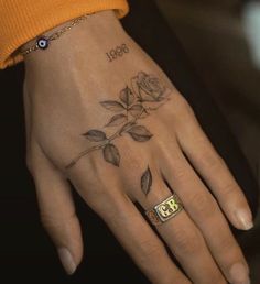 a woman's hand with a rose tattoo on it and the number 3 in gold