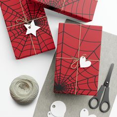 two wrapped gift boxes with scissors and twine on the table next to them,