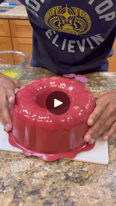 a person is decorating a cake with red icing