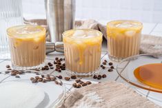 three glasses filled with drinks sitting on top of a table next to plates and spoons