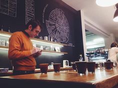 a man standing in front of a counter using his cell phone and looking at the screen