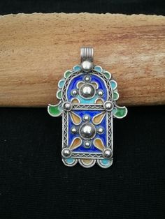 "A cute little silver and enamel Berber Khamsa pendant. Fully handmade, this Khamsa features tricolour enamel done in the traditional cloisonne technique with additional turquoise blue enamel accents and decorative dropwork.  Khamsa / \"Hand of Fatima\": Traditionally worn as a protective feminine symbol, the Khamsa (literally the number 5 in Arabic) is representative of the hand of the daughter of the prophet Mohammed. In Islam, Fatima is regarded as an exemplar for women. This ancient symbol is a wonderful example of religious syncretism amongst matriarchal Berbers who converted to Islam and Judaism. It was believed to bring good luck to the wearer. Silver: Hallmark on rear. Weight: 15,7 grams Shipping : DHL EXPRESS 🙂" Traditional Hallmarked Enamel Jewelry, Traditional Engraved Enamel Necklaces, Traditional Blue Necklaces With Inlay, Traditional Engraved Blue Jewelry, Traditional Blue Inlay Necklaces, Traditional Blue Necklace With Inlay, Traditional Enamel Pendant Jewelry, Traditional Blue Inlay Jewelry, Traditional Silver Jewelry With Inlay