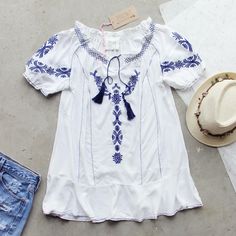 Gorgeous embroidered details adorn this tunic. Designed with a soft white base, navy embroidered details throughout, a tassel tie neck, short sleeves, and a breezy tunic fit. Color: White & navy 65% cotton & 34% rayon Imported Hand wash cold split Small/Medium Medium/Large Bust 38 40 Waist 37 39 Hips 39 41 Length 30 30 Bust, waist, and hip measurements are a total circumference. Length is measured from the top of the top to the hem. Measurements are an estimate. Casual Short Sleeve Tops With Tassels, Summer Blouse With Tassels And Short Sleeves, Summer Short Sleeve Blouse With Tassels, Blue Tassel Blouse For Summer, Summer Cotton Tunic With Short Sleeves, Short Sleeve Cotton Blouse With Tassels, Casual Short Sleeve Embroidered Summer Top, Blue Tassel Tops For Summer, Casual Cotton Blouse With Tassel Ties