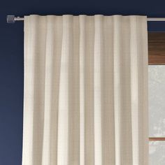 a white curtain hanging on the side of a window in front of a blue wall