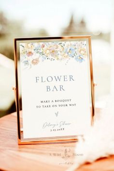 a flower bar sign sitting on top of a wooden table