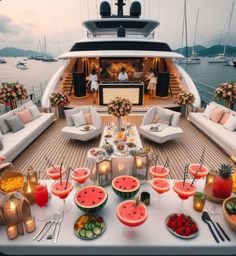 a table filled with watermelon slices and drinks on top of a wooden deck