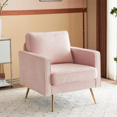 a pink chair sitting on top of a rug next to a white vase filled with flowers