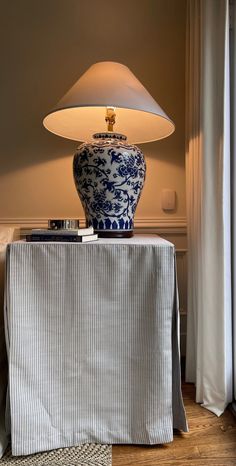 a blue and white vase sitting on top of a wooden table next to a lamp