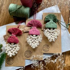 three small christmas ornaments on top of brown envelopes next to twine of yarn