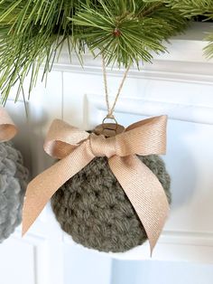 two ornaments hanging from the side of a christmas tree with a bow on it's ornament