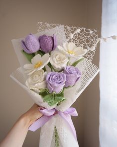 a person holding a bouquet of flowers in front of a white curtain with lace on it