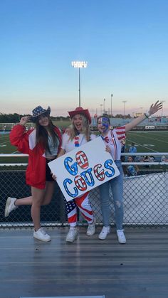 three girls in patriotic outfits holding a sign that says god's college on it