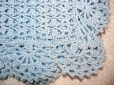 a blue crocheted blanket is laying on the floor