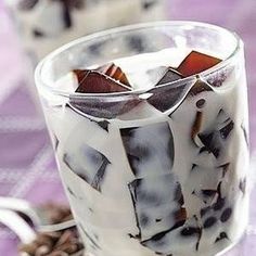 two glasses filled with ice cream and topped with coffee beans on a purple tablecloth