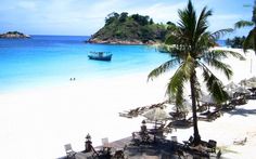 an empty beach with chairs and umbrellas on the sand next to blue water, surrounded by palm trees