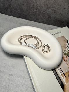 a pair of bracelets sitting on top of a white table next to a book