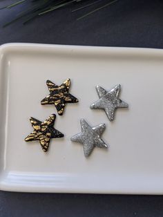 three small silver and gold stars on a white plate