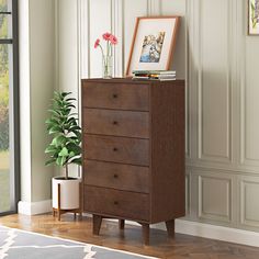 a wooden dresser sitting next to a potted plant on top of a hard wood floor