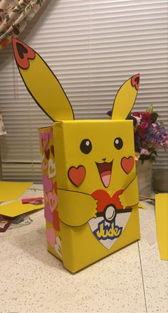 a box shaped like a pikachu sitting on top of a counter next to flowers