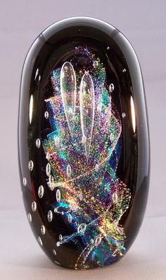 an artistically designed glass object on a white surface with lots of colors and sparkles