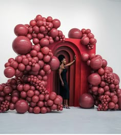 a woman standing in a doorway surrounded by red balls