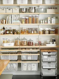 an organized pantry with clear bins and wooden shelves