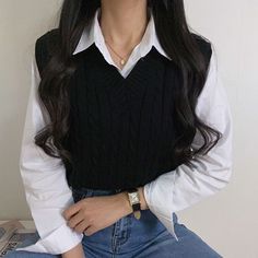 a woman with long dark hair wearing a white shirt and black vest