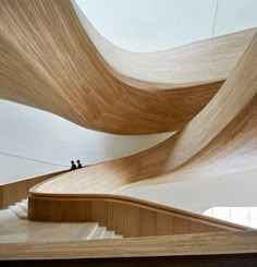 two people are standing on the top of a wooden staircase that is made of wood