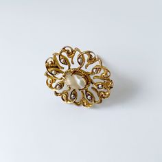 The listing is for a Vintage Seed Pearl Brooch. The brooch features a prong set mother of pearl flat cabochon with beautiful open work swirling gold frame. The decoratively engraved gold frame is accented with 8 small seed pearls set around the center mother of pearl flat cabochon. Measurement: 0.879 inches long x 0.982 inches wide. Weight: 3.4 grams Markings: unmarked but tests as 10K. Condition: Excellent condition. Has a working C-clasp closure. ❤All items in my shop are Estate, Vintage, and Yellow Gold Filigree Brooches For Wedding, Ornate Yellow Gold Wedding Brooch, Wedding Yellow Gold Filigree Brooches, Elegant Yellow Gold Baroque Brooches, Elegant Baroque Wedding Brooches, Ornate Yellow Gold Brooch For Formal Occasions, Elegant Wedding Brooch With Cabochon Detail, Elegant Gold Filigree Brooches, Gold Brooches With Intricate Design For Wedding