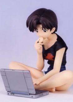 a figurine is sitting on the floor with a laptop in front of her