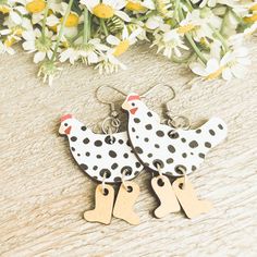 two white and black birds with wooden tags on them sitting next to some daisies