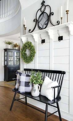 a bench with pillows and wreaths on it in front of a white painted wall