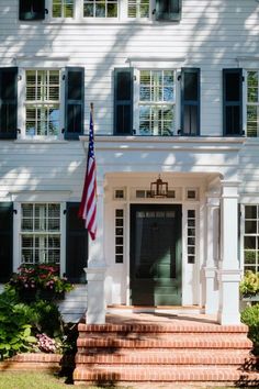 an american flag hangs on the front door of a white house