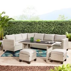 an outdoor patio furniture set with beige cushions and matching foot stools, on a blue area rug