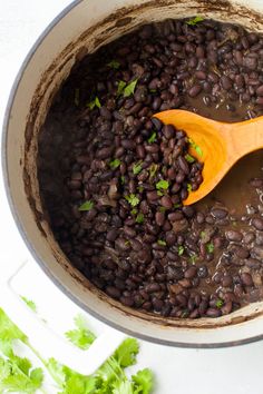 a wooden spoon in a pot filled with black beans