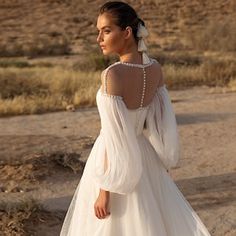 a woman in a wedding dress standing on the desert