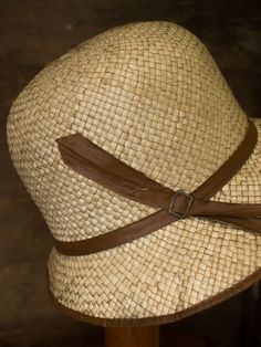 "An authentic antique woven cloche from the late 1920s or 30s era. Originally acquired by a European hat shop that closed in the 1930s. Made from a light colored woven straw with a simple yet elegant brown wax coated ribbon and buckle. Only minor signs of age from storage, never been previously used. Centimeter measurements written on the inside of the crown by the hat maker. material : straw color : brown, light beige condition : little to no wear, has never been used size : please review measu Vintage Brown Fedora Panama Hat, Vintage Brown Panama Hat With Curved Brim, Vintage Beige Brimmed Fedora, Vintage Brown Wide Brim Panama Hat, Vintage Brown Brimmed Panama Hat, Vintage Brown Adjustable Panama Hat, Vintage Natural Color Adjustable Hats, Vintage Brown Fedora Sun Hat, Vintage Brown Brimmed Boater Hat