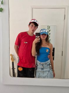 a young man and woman taking a selfie in front of a mirror with an electric guitar