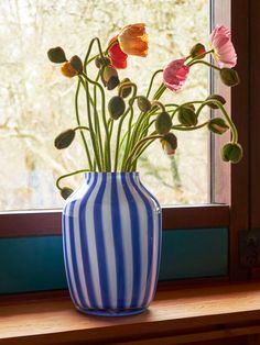 a blue and white striped vase with flowers in it