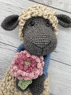 a crocheted sheep with a flower in its mouth